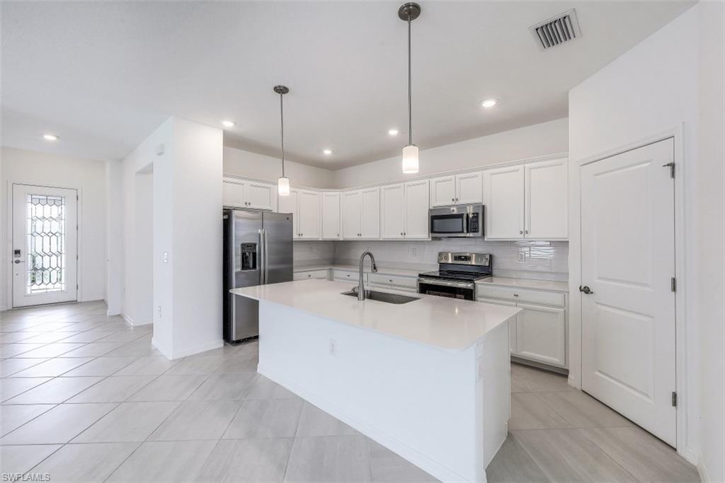 2434 Orchard Street Naples, FL 34120 - Photo 8 of 29 a kitchen with kitchen island a sink stainless steel appliances and cabinets