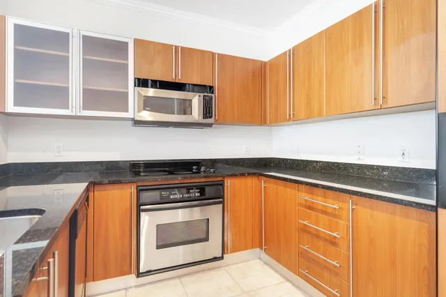 a kitchen with stainless steel appliances granite countertop white cabinets and a stove top oven