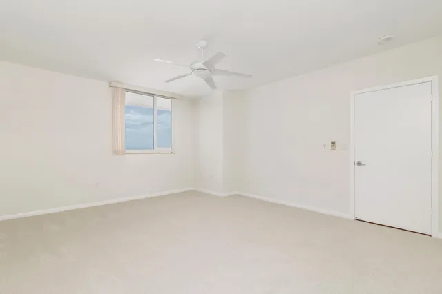 an empty room with a window and a fan