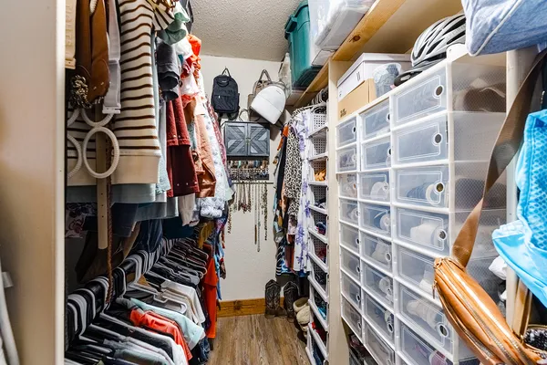 a view of walk in closet with clothes and shoes