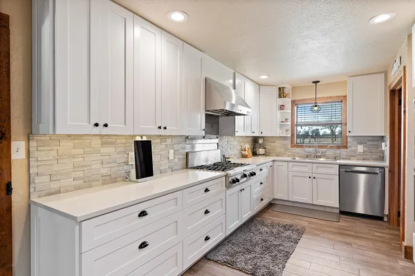 a kitchen with granite countertop white cabinets white stainless steel appliances with a sink and dishwasher