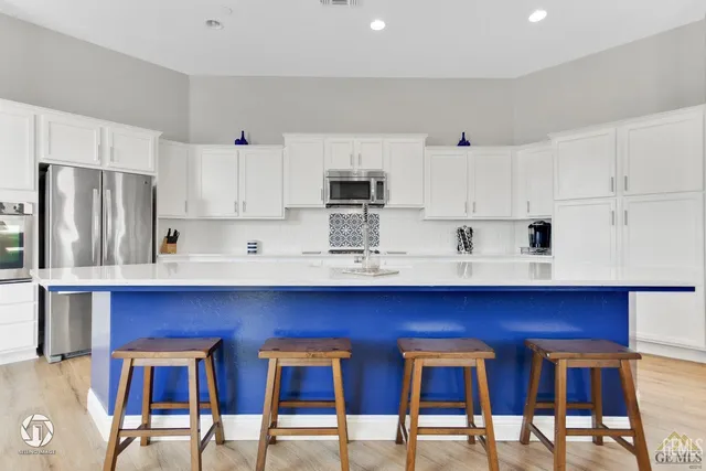 a kitchen with stainless steel appliances a table chairs refrigerator and microwave