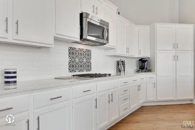 a kitchen with white cabinets and stainless steel appliances