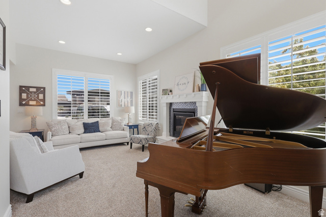 10676 Urban Rdg Cove South Jordan, UT 84095 - Photo 5 of 48 Open-concept living area featuring vaulted ceilings, recessed lighting, a fireplace with a white mantel and dark tile surround, and expansive windows with plantation shutters