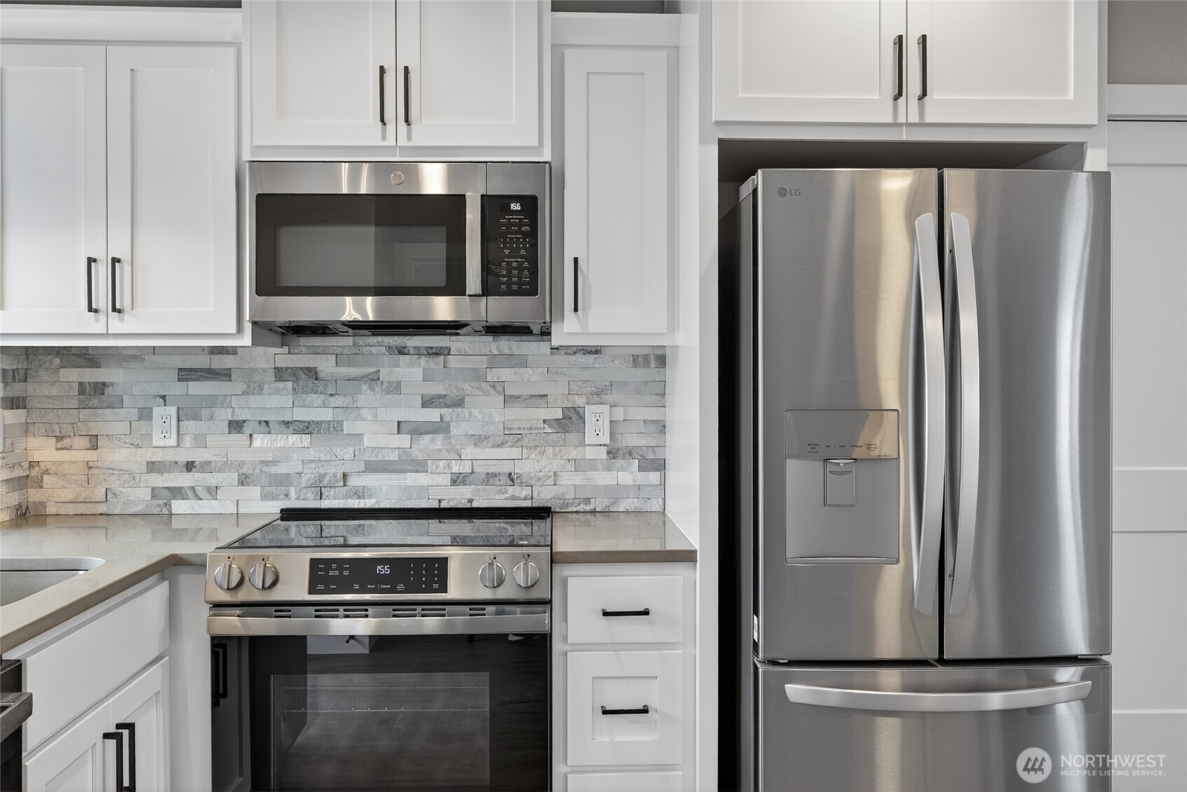 109 7th Street Southwest Long Beach, WA 98631 - Photo 8 of 22 a kitchen with stainless steel appliances white cabinets white stove a microwave and a refrigerator