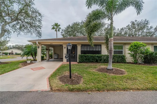 a front view of a house with a yard and palm trees