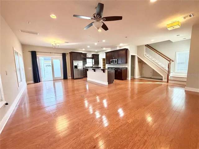 a view of a living room a kitchen island wooden floor and appliances
