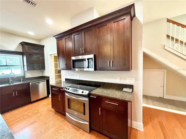 a kitchen with stainless steel appliances granite countertop a stove a sink and a microwave