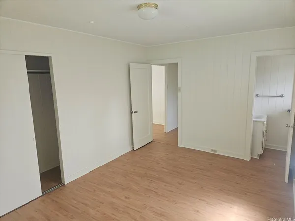 a view of an empty room with wooden floor and closet