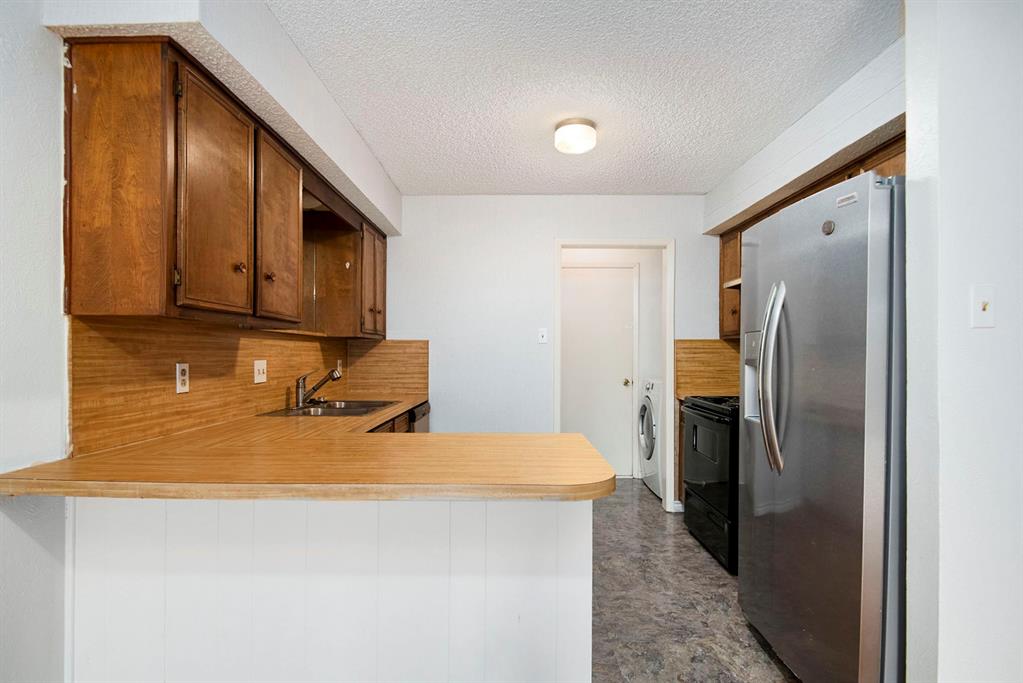 6817 West Cleburne Road Fort Worth, TX 76133 - Photo 12 of 24 a kitchen with a refrigerator and cabinets