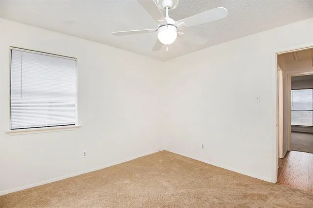 an empty room with a window and a fan
