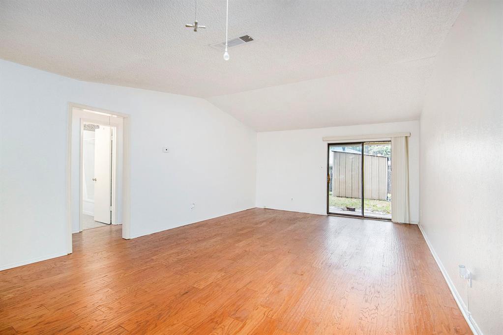 6817 West Cleburne Road Fort Worth, TX 76133 - Photo 7 of 24 a view of an empty room with wooden floor and a window