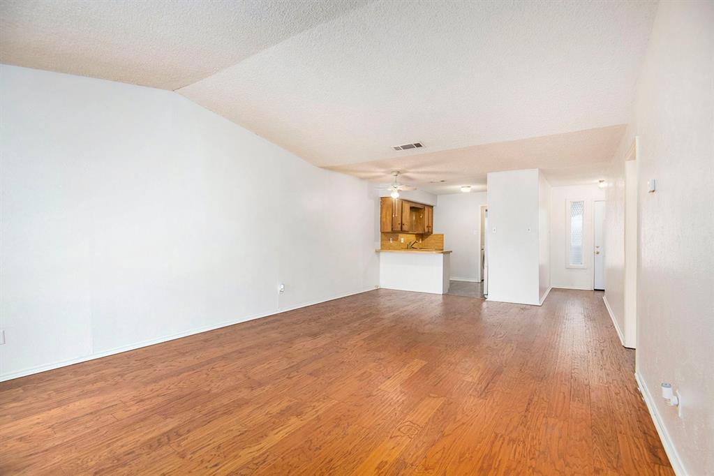 6817 West Cleburne Road Fort Worth, TX 76133 - Photo 10 of 24 a view of a big room with wooden floor and a kitchen