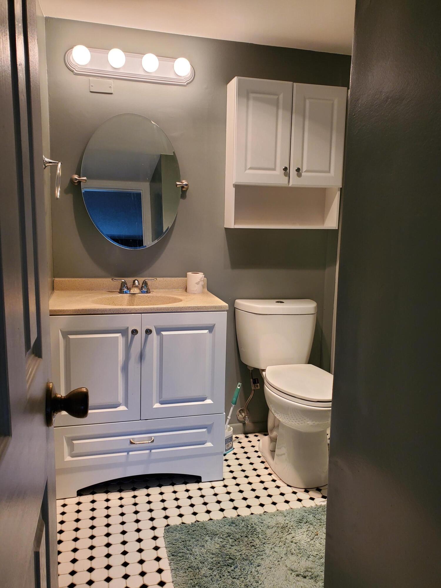 3300 Springdale Boulevard, Unit 318 Palm Springs, FL 33461 - Photo 16 of 34 a bathroom with a toilet a sink and mirror