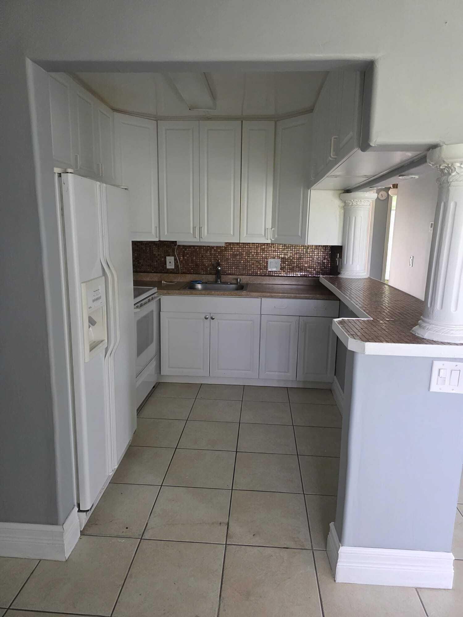 3300 Springdale Boulevard, Unit 318 Palm Springs, FL 33461 - Photo 6 of 34 a kitchen with granite countertop a sink a stove and a refrigerator