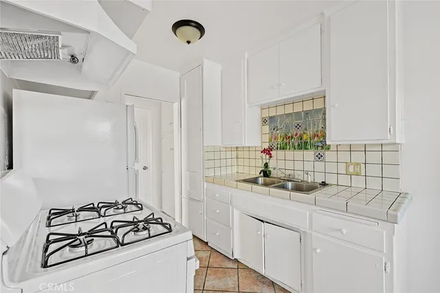 a kitchen with sink a stove and white cabinets