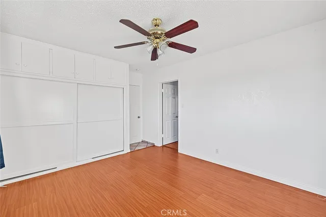 an empty room with wooden floor and a ceiling fan