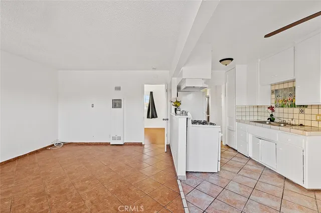 a room with a kitchen island a sink cabinets and stainless steel appliances