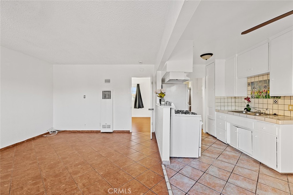 330 West Laurel Street, Unit C Compton, CA 90220 - Photo 4 of 16 a room with a kitchen island a sink cabinets and stainless steel appliances