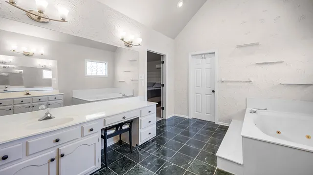 a spacious bathroom with a double vanity sink mirror and a bathtub