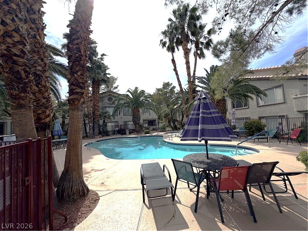4955 South Lindell Road, Unit 203 Las Vegas, NV 89118 - Photo 31 of 31 An inviting community pool surrounded by palm trees and lounging areas awaits.