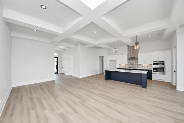 a large kitchen with stainless steel appliances wooden floor and a large window