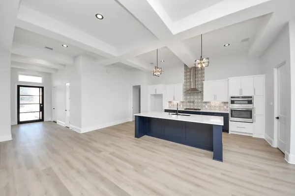 a large kitchen with stainless steel appliances a large counter top a sink a refrigerator and a window