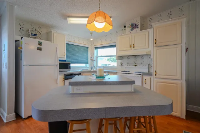 a kitchen with stainless steel appliances granite countertop a refrigerator a sink dishwasher a stove and white cabinets with wooden floor