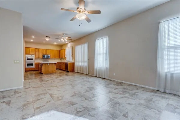 an empty room with a chandelier fan and windows