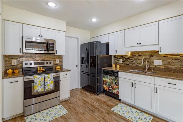 a kitchen with stainless steel appliances granite countertop a refrigerator stove and sink