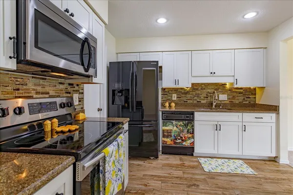 a kitchen with stainless steel appliances granite countertop a stove refrigerator and microwave