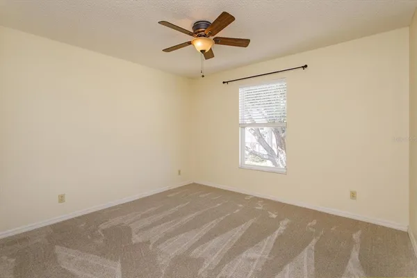 an empty room with a window and a fan