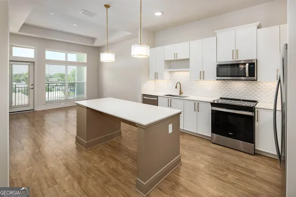 a kitchen with stainless steel appliances granite countertop a stove top oven a sink dishwasher and a refrigerator with wooden floor