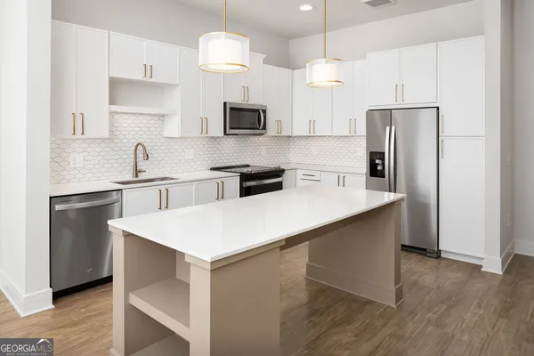 a kitchen with kitchen island white cabinets a sink a refrigerator and a stove