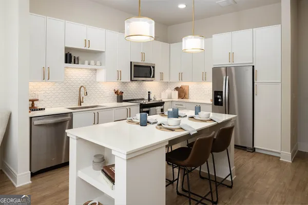 a kitchen with stainless steel appliances a table chairs refrigerator and microwave