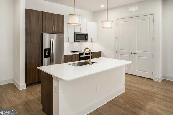 a kitchen with a white center island a refrigerator and cabinets