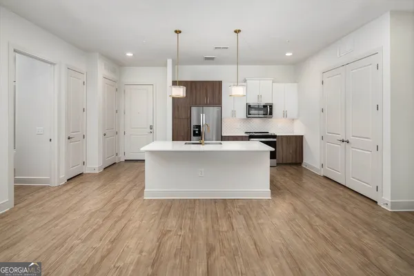 a kitchen with stainless steel appliances kitchen island wooden floors and white cabinets