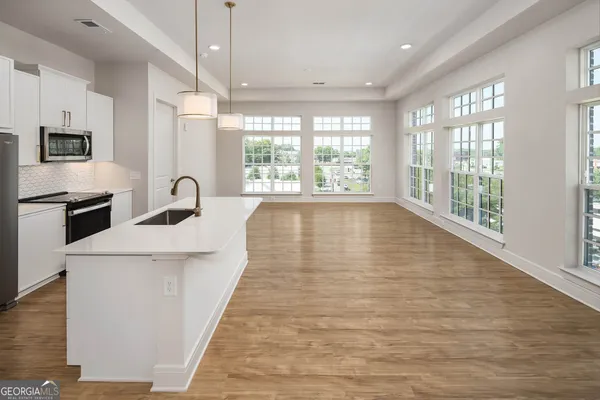 a large white kitchen with wooden floor and a window