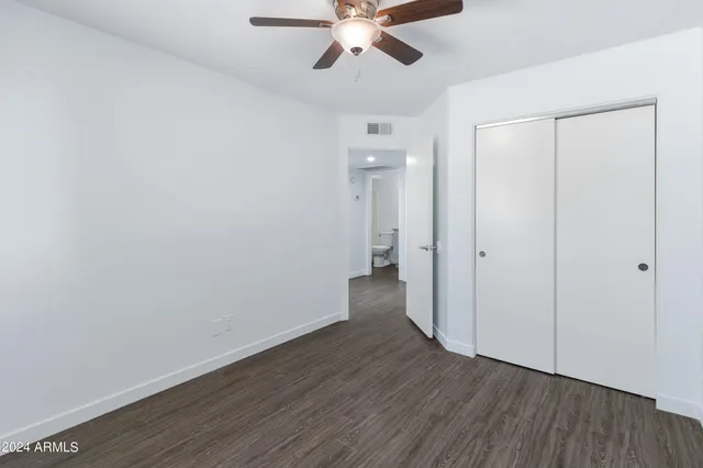 an empty room with wooden floor fan and windows