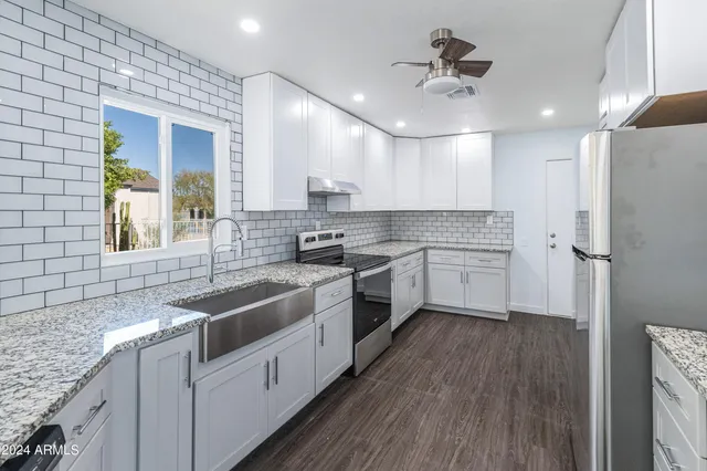 a kitchen with granite countertop a sink stainless steel appliances cabinets and a counter space