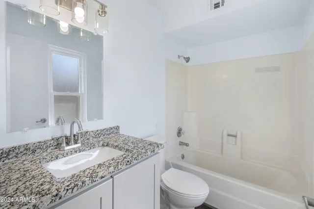 a bathroom with a granite countertop sink a toilet and shower