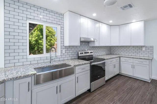 a kitchen with a sink white cabinets and white appliances