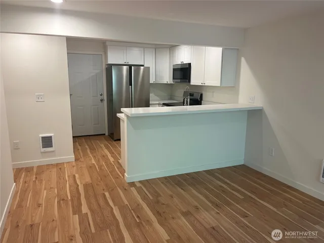 a kitchen with wooden floors and white stainless steel appliances