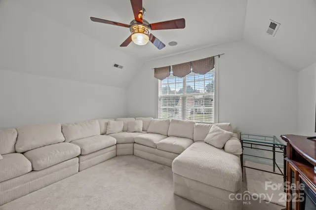 a living room with furniture a ceiling fan and a window