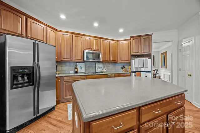 a kitchen with stainless steel appliances a refrigerator a stove a sink a center island and a refrigerator