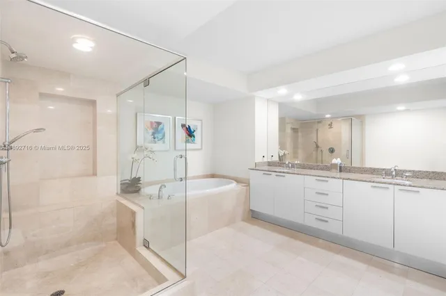 a large white bathroom with a double vanity sink a mirror and a bathtub