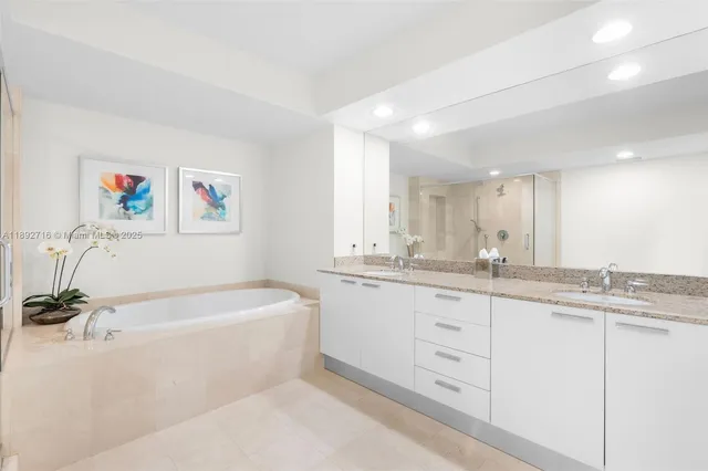 a bathroom with a granite countertop sink a large mirror a bathtub and shower