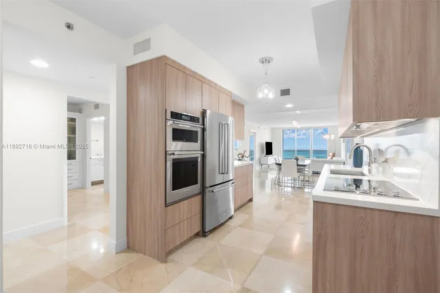 a kitchen with stainless steel appliances kitchen island granite countertop a refrigerator and a sink