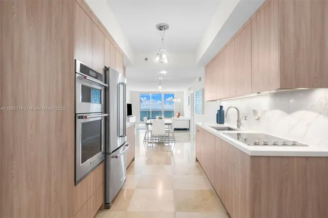 a kitchen with stainless steel appliances granite countertop a refrigerator a sink dishwasher a stove and white cabinets with wooden floor