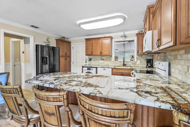 a kitchen with kitchen island granite countertop a table chairs a stove a microwave and cabinets